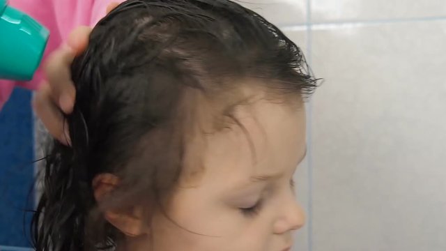 The child's hair is dried. A little girl is doing her hair.