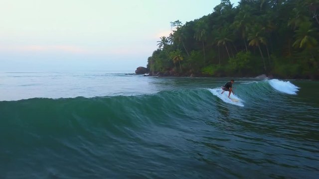 Aerial view surfer catch the wave an fall in ocean at sunset drone footage