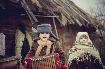 Rural boy in old clothes playing the accordion. Village girl singing.