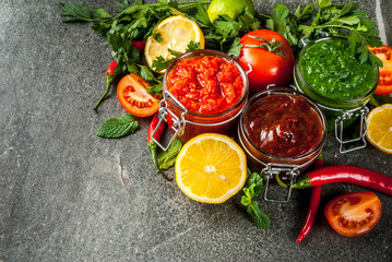 Indian traditional food, Set of three chutney for Chaat and Sev Puri - sweet date-tamarind, cilantro-mint green and red chilli garlic, On dark stone background, copy space