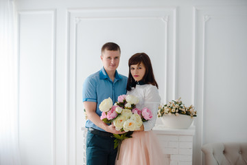 Adorable loving couple in a white room with at home. indoor portrait of handsome young man and young girl