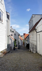 Fototapeta na wymiar View of street with traditional white wooden houses in Gamle Stavanger in Rogaland, Norway, sunny day with blue sky