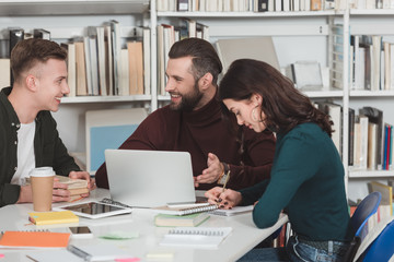 three students studying with laptop in library