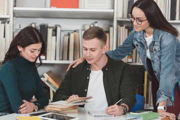multiethnic friends studying in library and looking at book