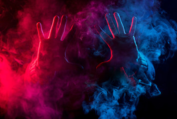 hands in colorful smoke on black background