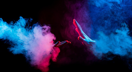 hands reaching from colorful smoke on black background © arts