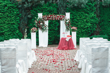 Wedding ceremony. Arch, decorated with red and white roses, in the wedding ceremony area