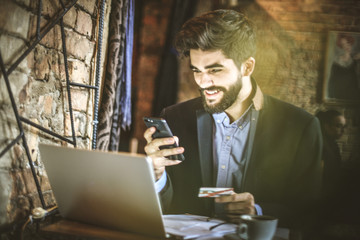 Young business man using smart phone to pay bills online.