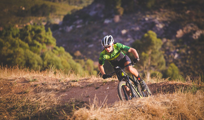 Obraz na płótnie Canvas Wide angle view of a mountain biker speeding downhill on a mountain bike track in the woods
