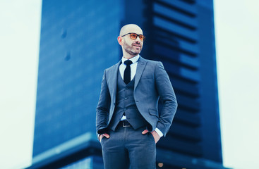 portrait of a successful young business man in a gray suit against the background of a business center