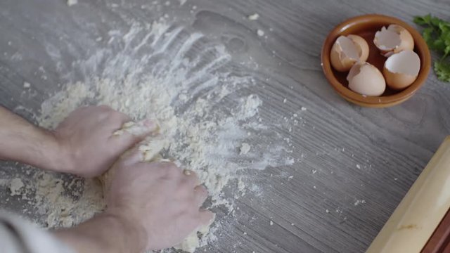 Man preparing dough on kitchen table, top view.