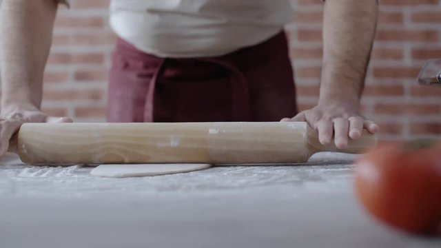 man rolling out dough on a cutting board while making pasta