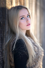 Portrait of a young blond woman with long healthy hair in winter park.