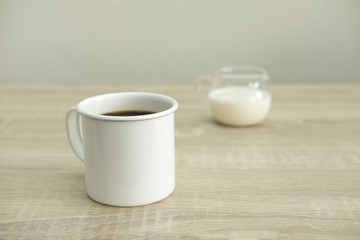 WHITE ENAMEL COFFEE MUG WITH MILK JAR
Enamel white coffee mug with milk jar on a wood table.