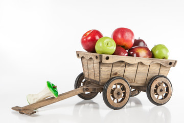 A wooden cart with apples. The cart is filled with red apples. Harvesting of apples.