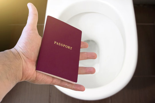 Hand holds the citizen's passport over the toilet, throw out his passport. Concept - change of citizenship, loss of passport, political problems, infringement of rights.