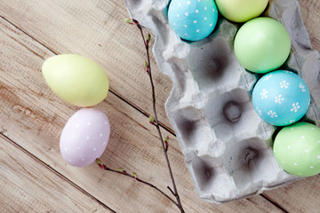 Fototapeta na wymiar Rustic easter border on wooden background with yellow, pink, green and blue colored eggs in box. Easter. Orthodox holiday. Wooden background.