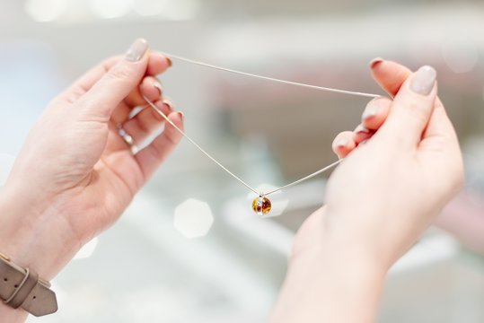 Woman Owner Of Jewelry Shop Presenting Silver Necklace With Amber