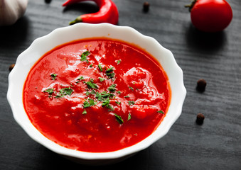 Traditional Italian tomato soup gazpacho in bowl on dark wooden background