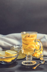 Tea with ginger and lemon in a glass cup and yellow sweets on a wooden background