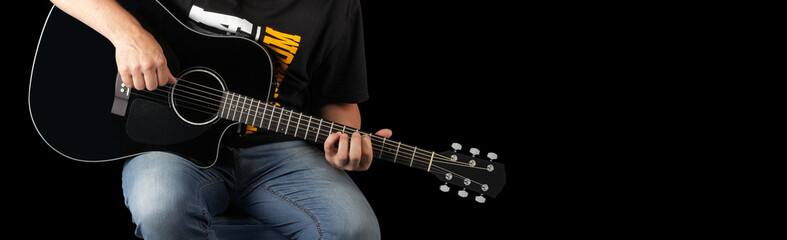 Fototapeta na wymiar Music - Fragment Man play a black acoustic guitar black background