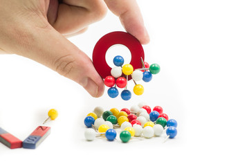 round red and blue magnet attracting metal paper pins in a hand isolated on white