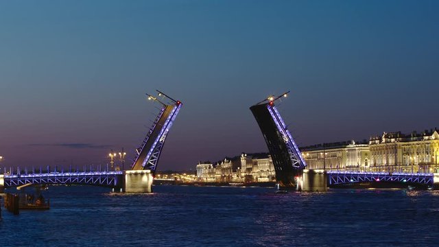 Opened Palace Bridge on the Neva river and illuminated buildings in the night