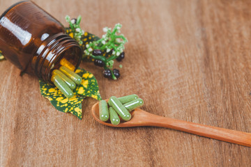 Herbal medicine capsules in wooden spoon ,soft focus.