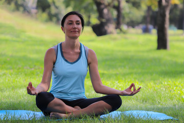 Middle-aged woman doing yoga pose meditation in the public park, Healthy body posture with happy feeling in the morning. Sport concept.