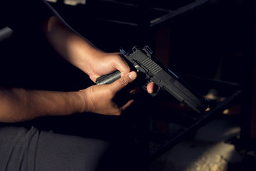 Close up, Hand of a man carrying a magazines gun. There is a bullet in the chamber. Prepare to used protect yourself. He dodged in a dark room with sunlight. Blur and soft focus. 