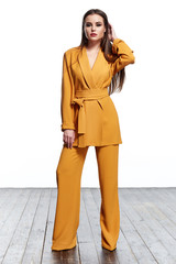 Beautiful sexy pretty girl wear yellow suit jacket and pants skinny body shape lady boss business woman skin tan long brunette hair party office date style fashion cloches accessory jewelry studio.