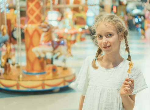 Cute little girl with lollipop in amusement park.