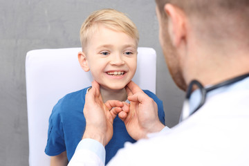 Chore dziecko u lekarza. Badanie lekarskie. Pediatra sprawdza węzły chłonne na szyi chłopca - obrazy, fototapety, plakaty