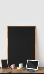 empty blackboards in frames with cups and laptop on table on white