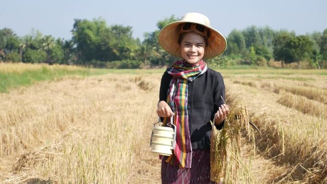 4k video of farmer woman smiling and looking around  with tiffin carrier in rice field, Thailand