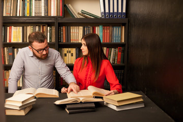a man and a woman read a lot of books in the library
