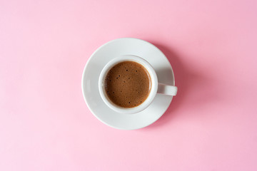Obraz na płótnie Canvas A cup of espresso with foam in a white cup on a white saucer on a vivid pink background. Place for text. Flat lay