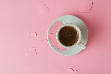 Obraz na płótnie Canvas A cup of espresso with foam in a white cup on a white saucer on a vivid pink background. Creative decor with paper hearts on the valentine's day. Wedding table. Holidays. Flat lay