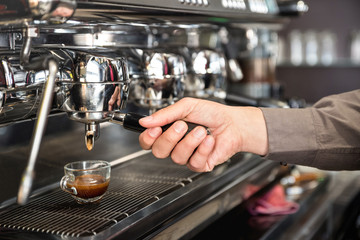 Classic barman hand preparing italian espresso at modern coffee bar machine in fashion cafeteria - Food and beverage concept with professional bartender at cafe stand working station - obrazy, fototapety, plakaty
