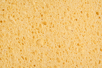 Yellow sponge cleansing puff for face or cleaning surface texture background on top view