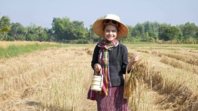 4k video of farmer woman smiling and looking around  with tiffin carrier in rice field, Thailand
