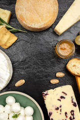 Various types of cheese on black with copy space