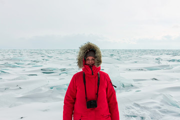 Portrait of a woman in a parka jacket with a fur hood in a snowy Baikal in hummocks