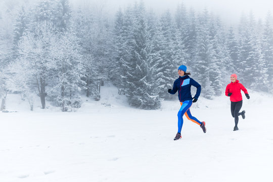 Two Women Trail Running On Snow In Winter Mountains