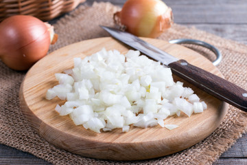 Raw onion, chopped cubes on a wooden board