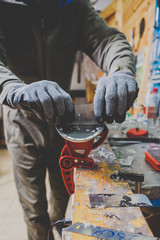 A male worker in a ski service workshop repairs the sliding surface of the skis. Close-up of a hand...
