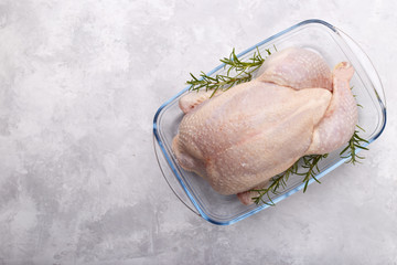 Raw whole chicken with salt and rosemary on stone background, copy space top view