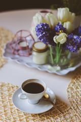 Morning coffee, spring decorations at home on the table in modern scandinavian style with flowers and aromatic candles. Slow living and hygge concept