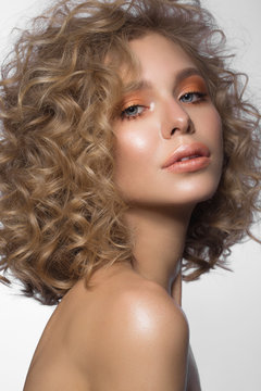Beautiful blonde girl with curls and gentle make-up. Beauty face. Photos shot in the studio.