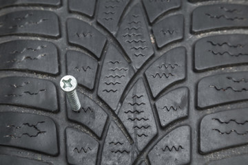 Screw in the black tire. Damaged tire problems and solutions concept.